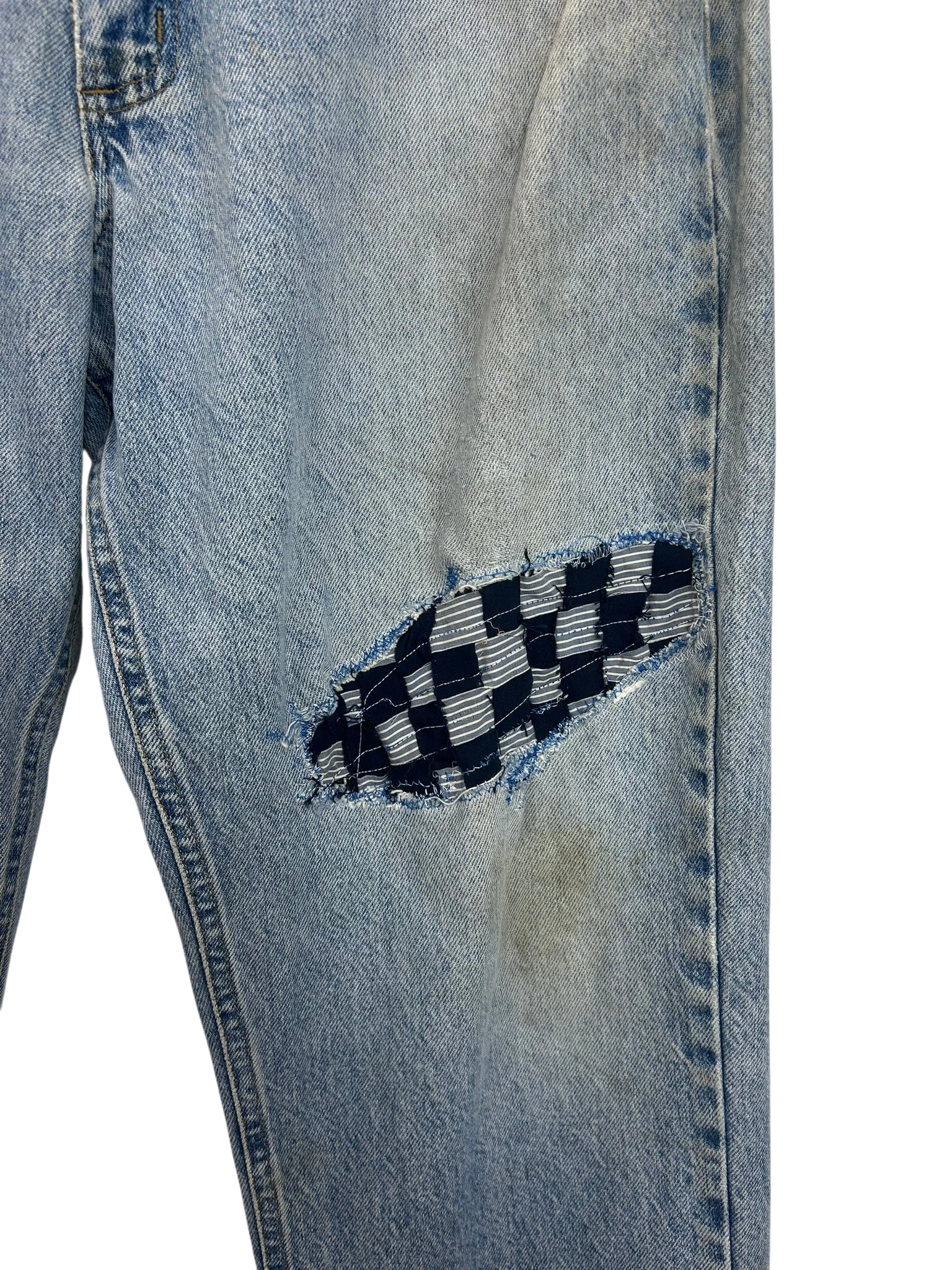 Lahad Vintage light wash denim jeans with a checkered patch repair on the knee.