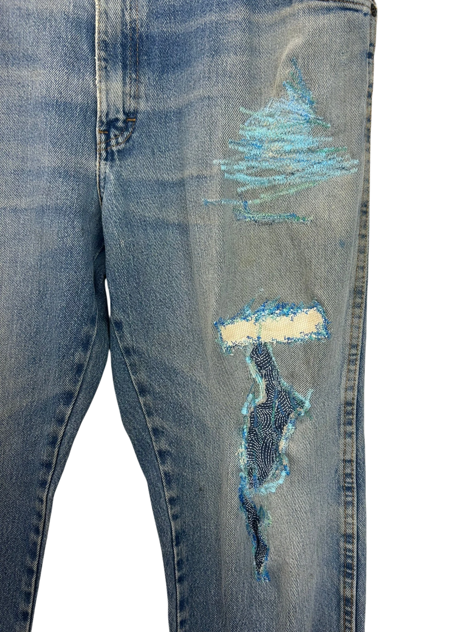 Lahad Vintage light wash denim jeans with distressed details and blue embroidered patches on the leg.