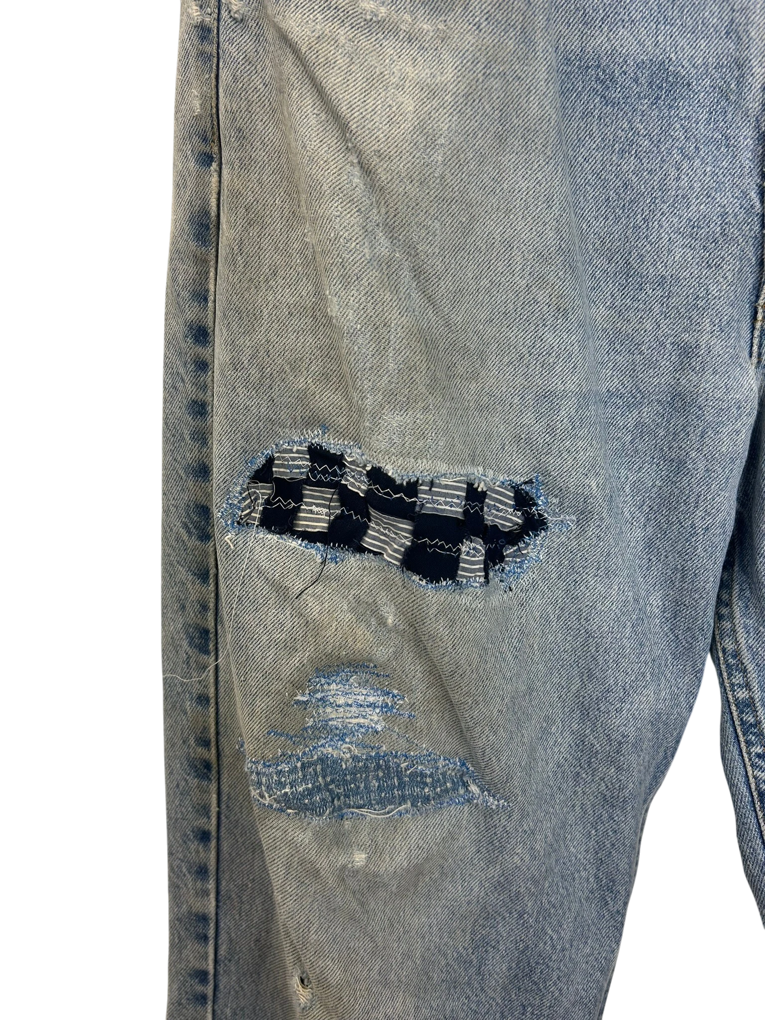 Lahad Vintage light wash denim jeans with distressed details and a checkered patch repair on the knee.