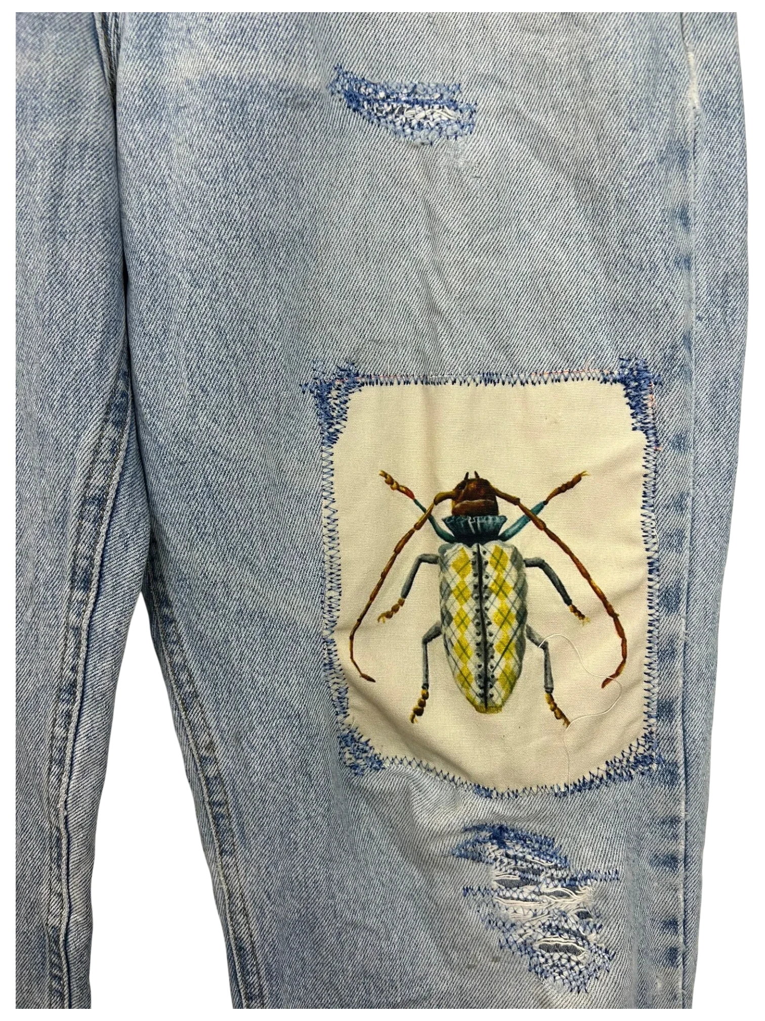 Lahad Vintage light wash denim jeans with distressed details and a unique embroidered beetle patch on the leg.