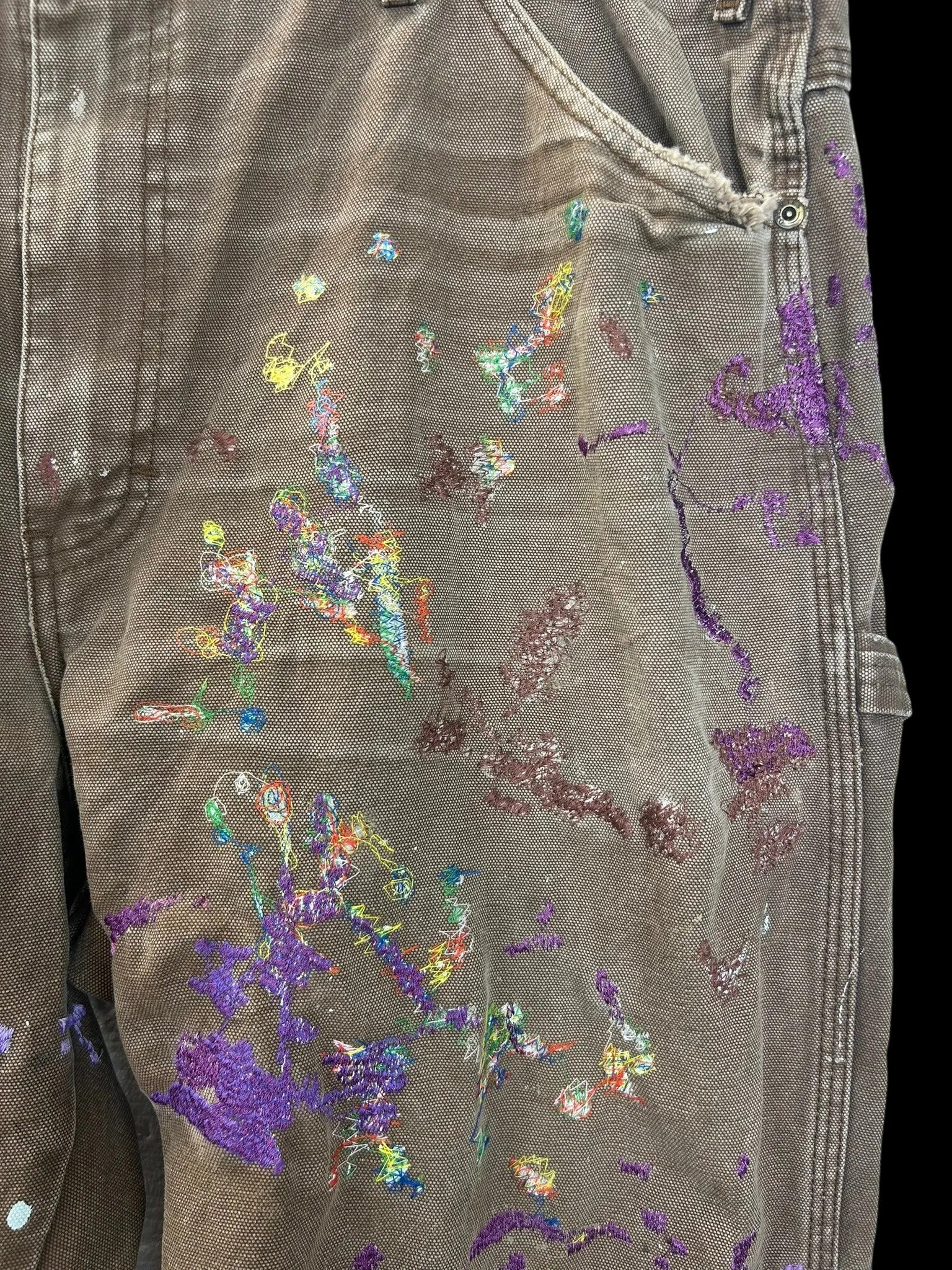 Lahad Vintage brown canvas carpenter pants with purple paint splatters and Metukan stitching. Multiple pockets for functionality.