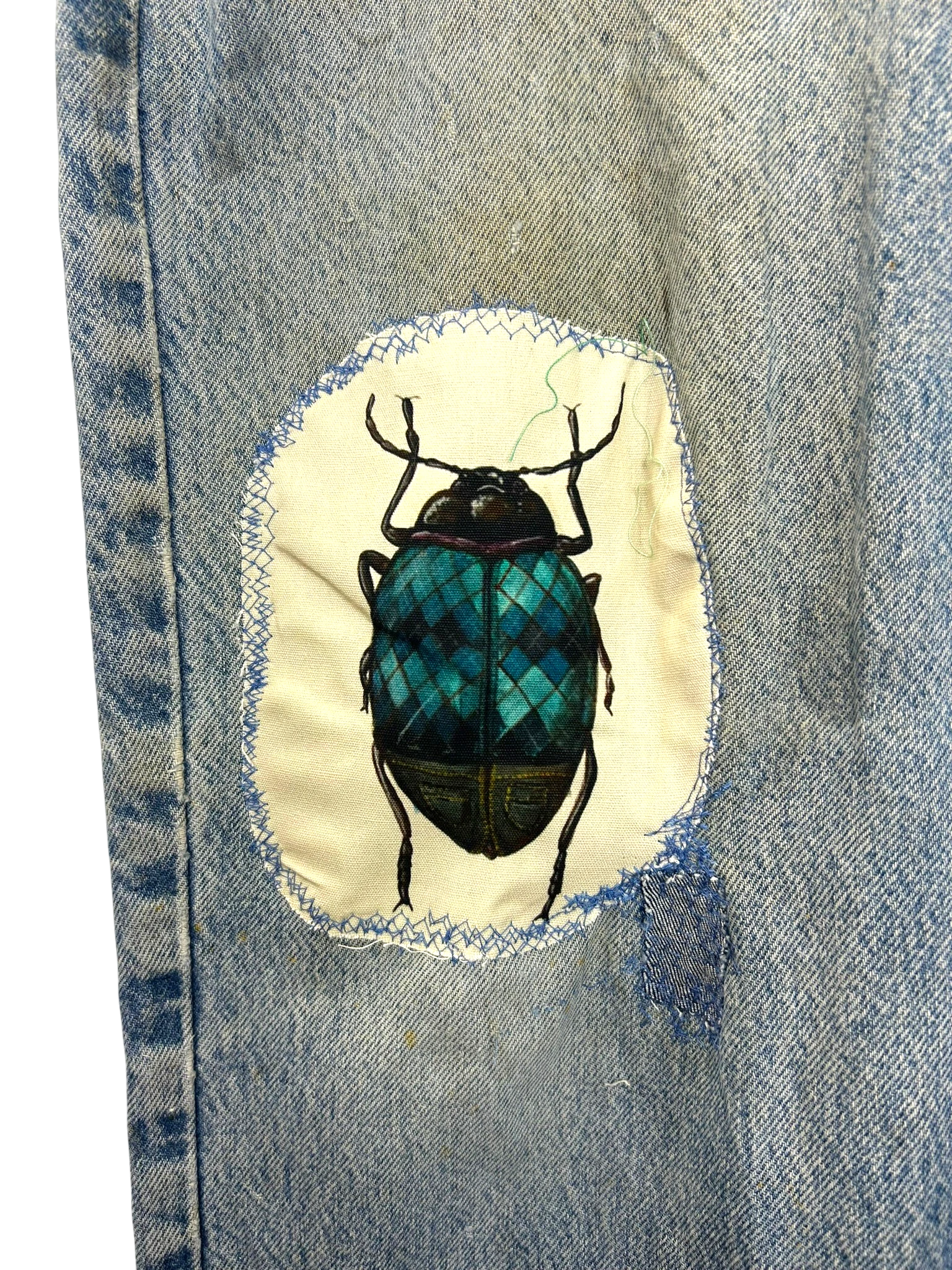 Lahad Vintage light-wash distressed denim jeans with embroidered beetle patch on thigh. Relaxed fit, vintage style.