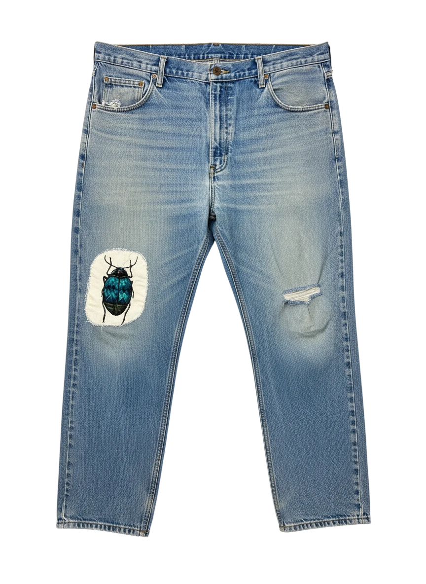 Lahad Vintage light-wash denim jeans with distressed details and a custom embroidered beetle patch on the left thigh.