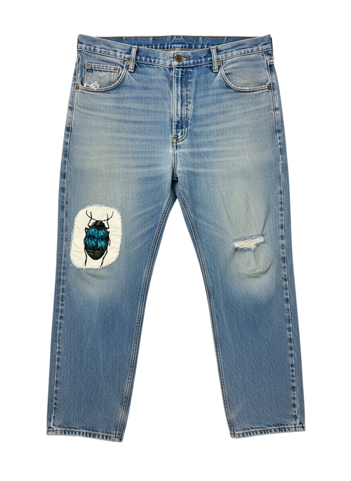 Lahad Vintage light-wash denim jeans with distressed details and a custom embroidered beetle patch on the left thigh.